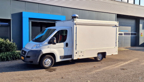 Zijaanzicht van een verkoopwagen voor diverse branches met gesloten luifel