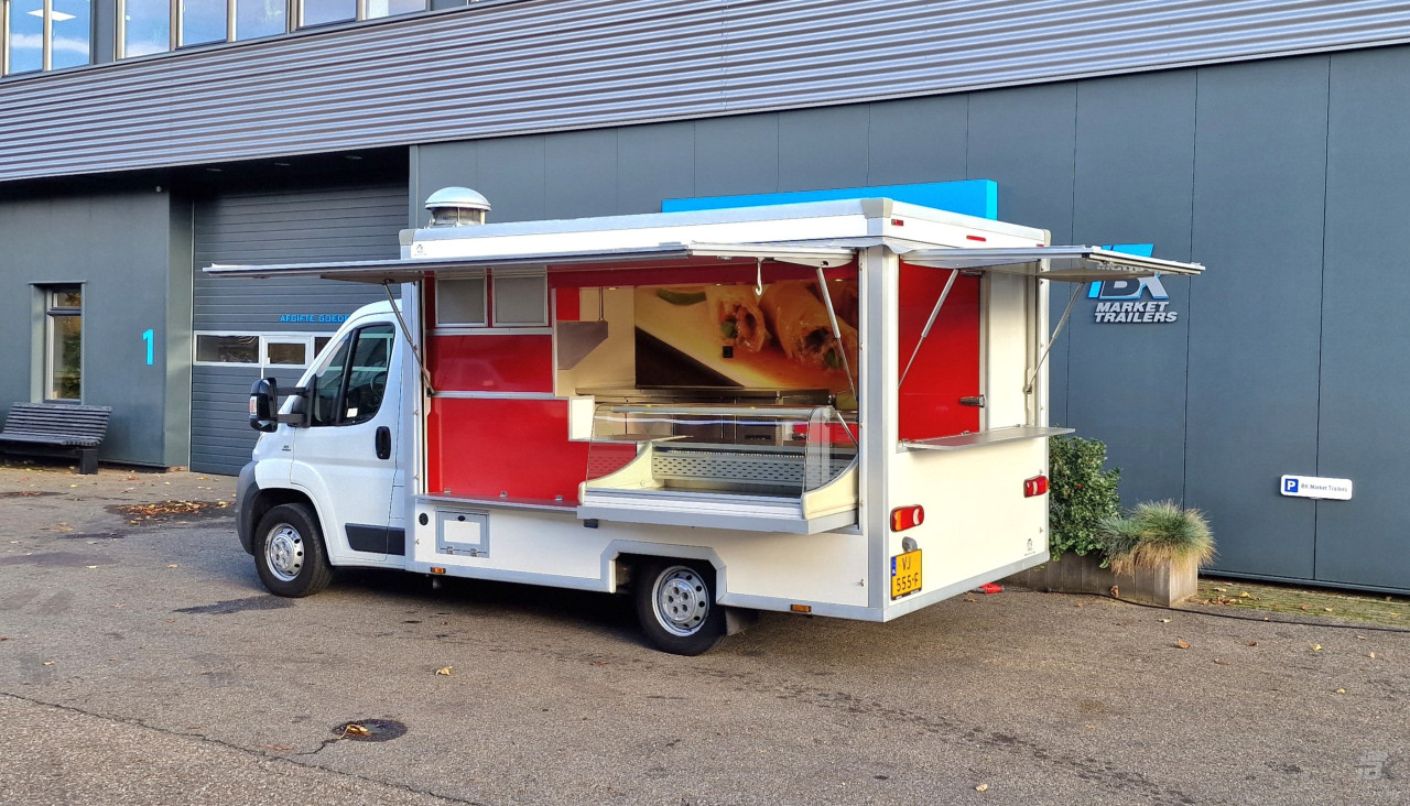 Zijaanzicht van een verkoopwagen voor diverse branches met geopende luifel