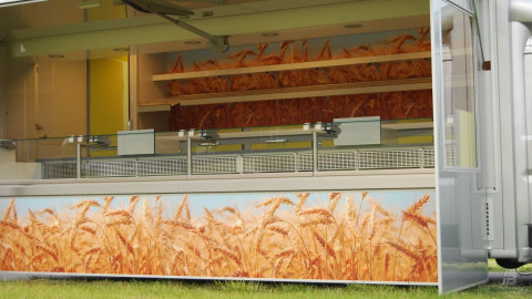 Zijaanzicht van een verkoopwagen voor brood met geopende luifel en zijbord