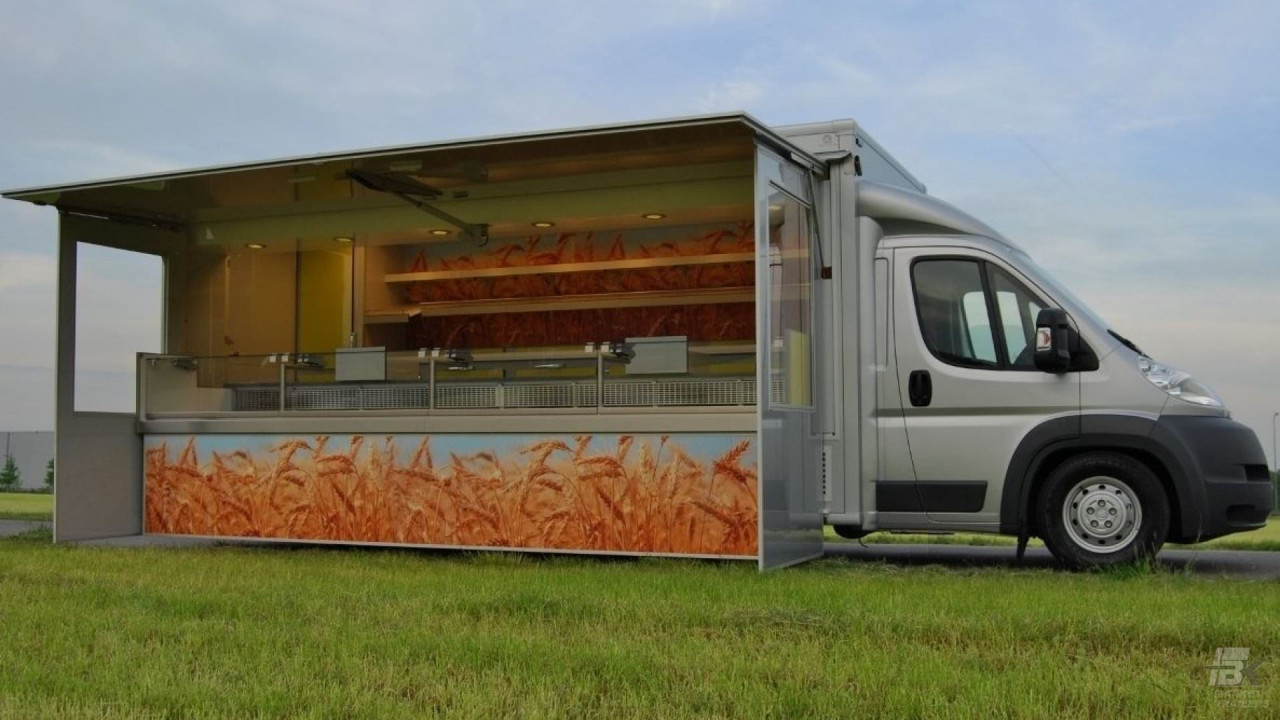 Zijaanzicht van een verkoopwagen voor brood met geopende luifel en zijborden