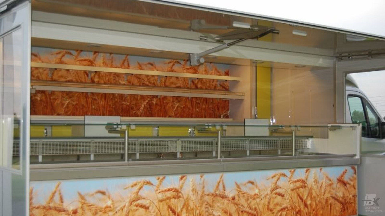 Zijaanzicht van een verkoopwagen voor brood met geopende luifel en zijborden