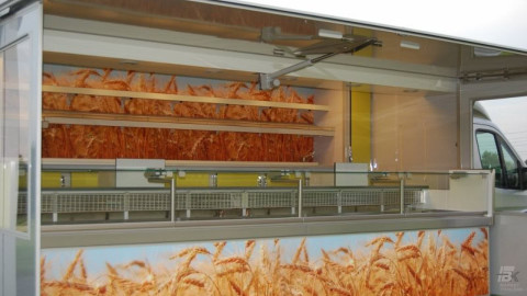 Zijaanzicht van een verkoopwagen voor brood met geopende luifel en zijborden