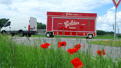 Zijaanzicht van een Iveco bestelwagen met aanhangwagen voor snacks met gesloten luifel