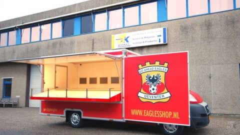 Zijaanzicht van een verkoopwagen voor promotie en merchandise met geopende luifel