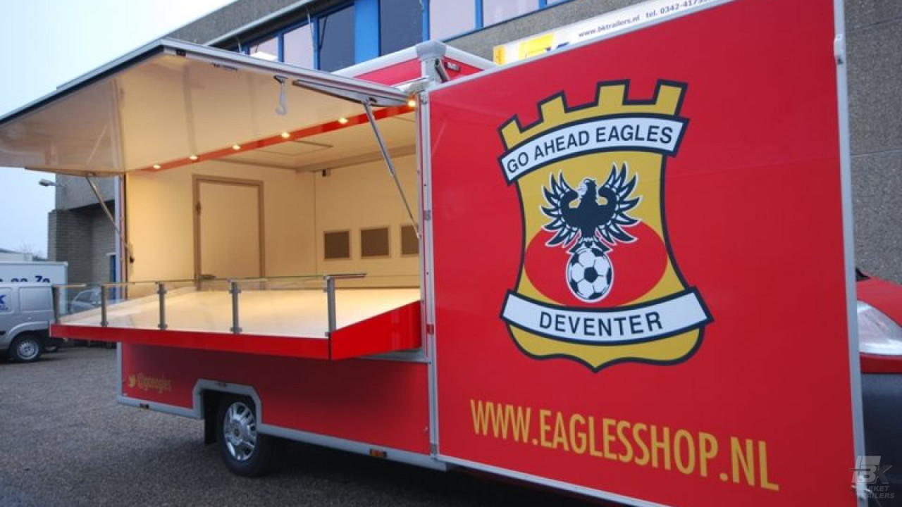 Zijaanzicht van een verkoopwagen voor promotie en merchandise met geopende luifel