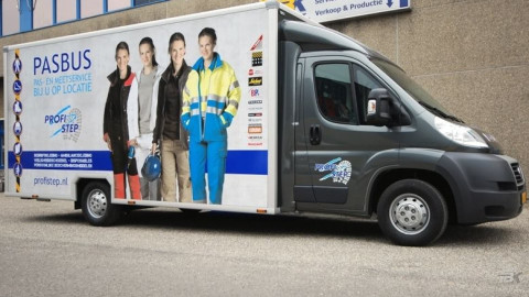 Zijaanzicht van een verkoopwagen voor bedrijfskleding met gesloten luifel