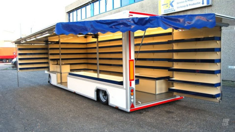 Zijaanzicht van een aanhangwagen voor drogisterijartikelen met geopende luifel