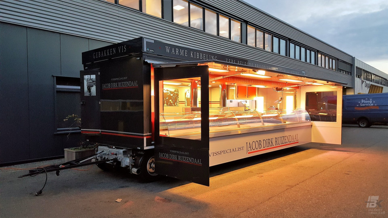 Zijaanzicht van een aanhangwagen voor vis met geopende luifel en zijborden