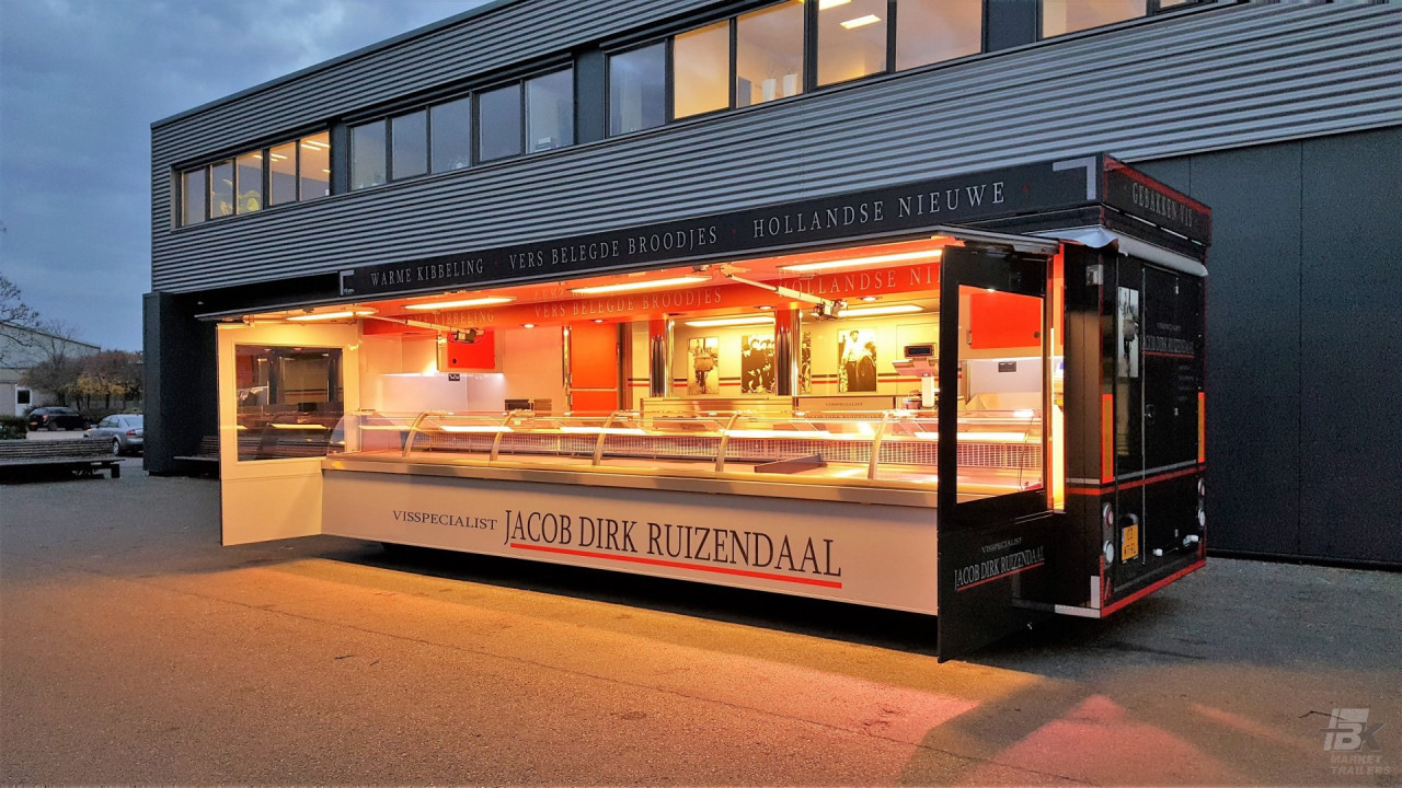 Zijaanzicht van een aanhangwagen voor vis met geopende luifel en zijborden