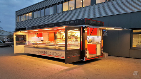 Zijaanzicht van een aanhangwagen voor vis met geopende luifel en zijborden
