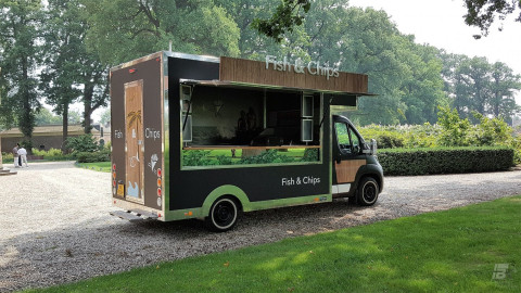 Zijaanzicht van een verkoopwagen voor vis en patat met geopende luifel