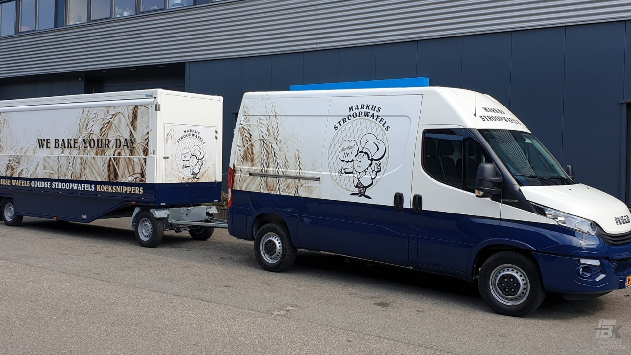 Zijaanzicht van een Iveco bus met aanhangwagen voor stroopwafels