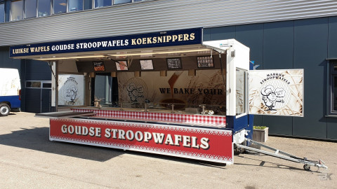 Zijaanzicht van een aanhangwagen voor stroopwafels met geopende luifel