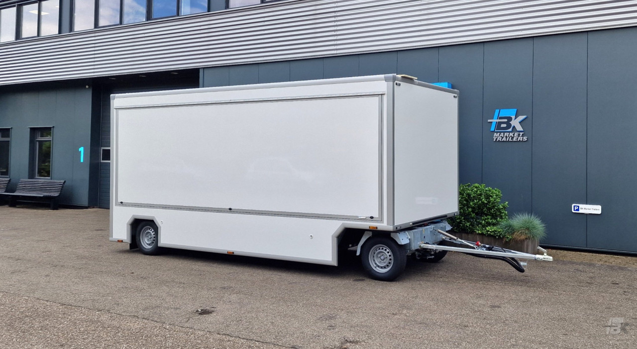 Zijaanzicht van een aanhangwagen voor diverse branches met gesloten luifel
