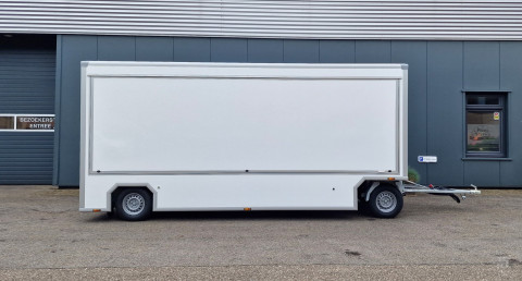 Zijaanzicht van een aanhangwagen voor diverse branches met gesloten luifel