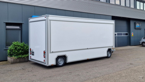 Zijaanzicht van een aanhangwagen voor diverse branches met gesloten luifel