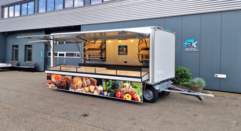 Zijaanzicht van een aanhangwagen voor diverse branches met geopende luifel