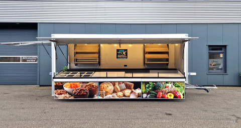 Zijaanzicht van een aanhangwagen voor diverse branches met geopende luifel