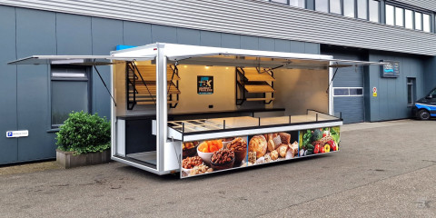 Zijaanzicht van een aanhangwagen voor diverse branches met geopende luifel