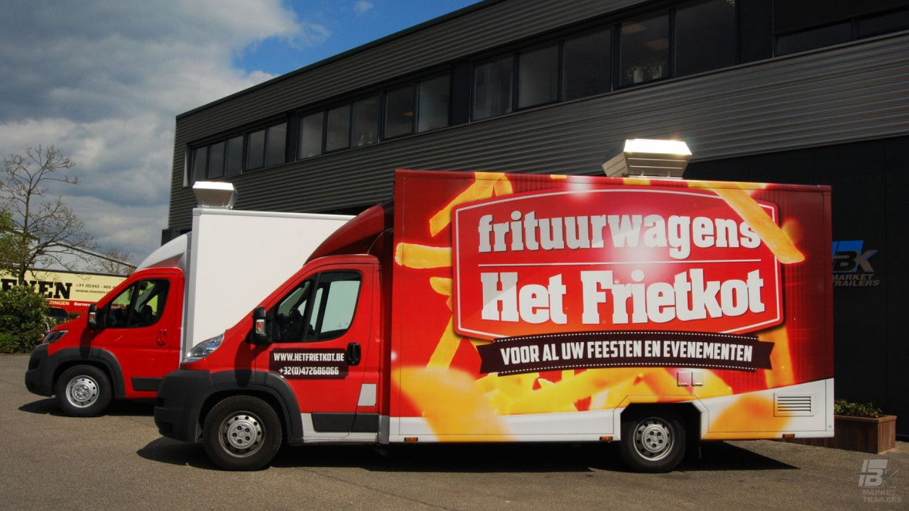 Zijaanzicht van twee verkoopwagens voor patat met gesloten luifels