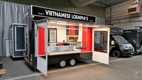 Zijaanzicht van een kleine aanhangwagen voor loempia's met geopende luifel