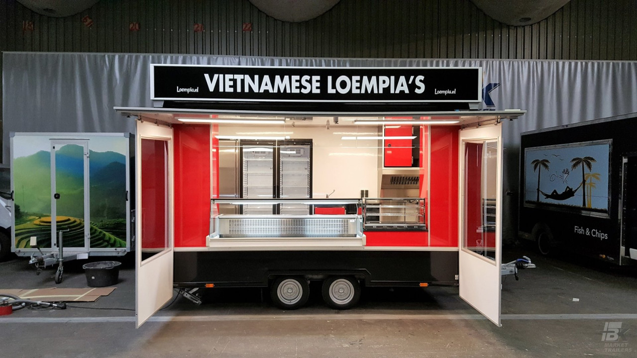 Zijaanzicht van een kleine aanhangwagen voor loempia's met geopende luifel
