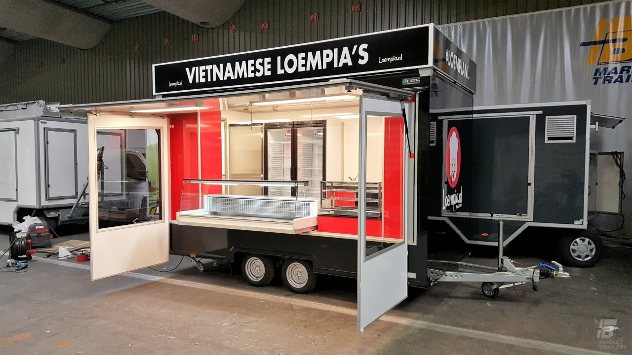 Zijaanzicht van een kleine aanhangwagen voor loempia's met geopende luifel