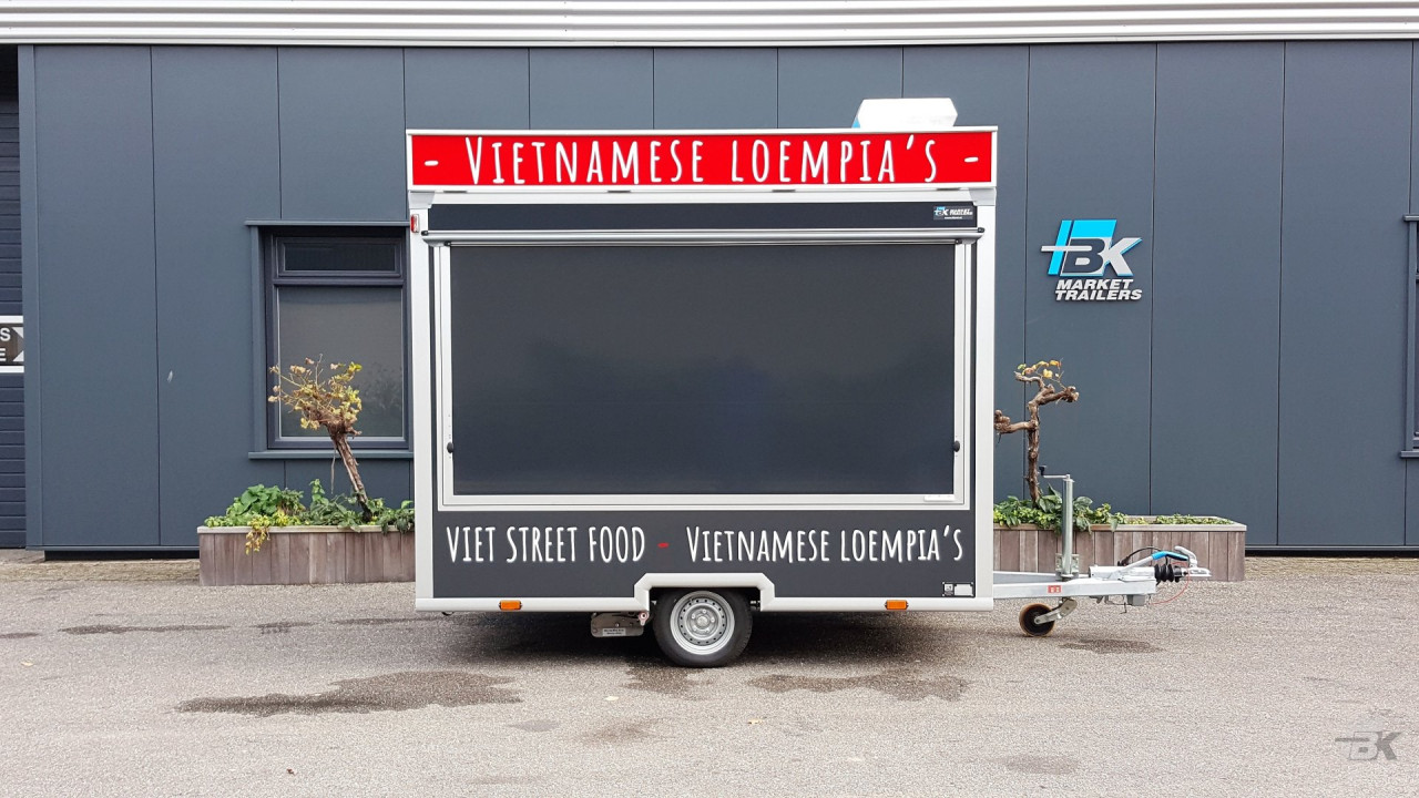 Zijaanzicht van een kleine aanhangwagen voor loempia's met gesloten luifel