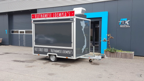 Zijaanzicht van een kleine aanhangwagen voor loempia's met gesloten luifel