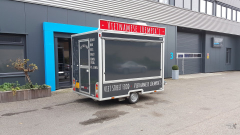 Zijaanzicht van een kleine aanhangwagen voor loempia's met gesloten luifel