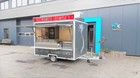 Zijaanzicht van een kleine aanhangwagen voor loempia's met geopende luifel