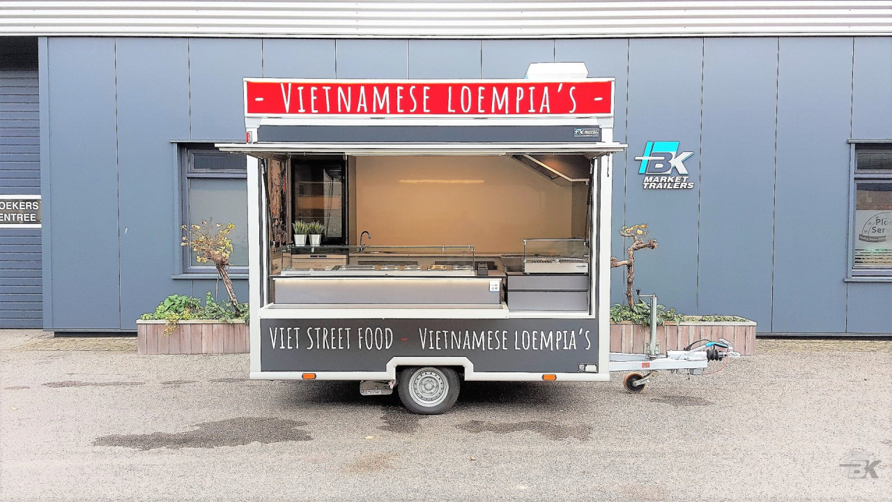 Zijaanzicht van een kleine aanhangwagen voor loempia's met geopende luifel
