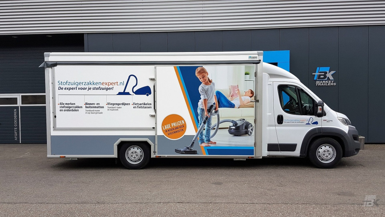 Zijaanzicht van een verkoopwagen voor stofzuigerzakken met gesloten luifel