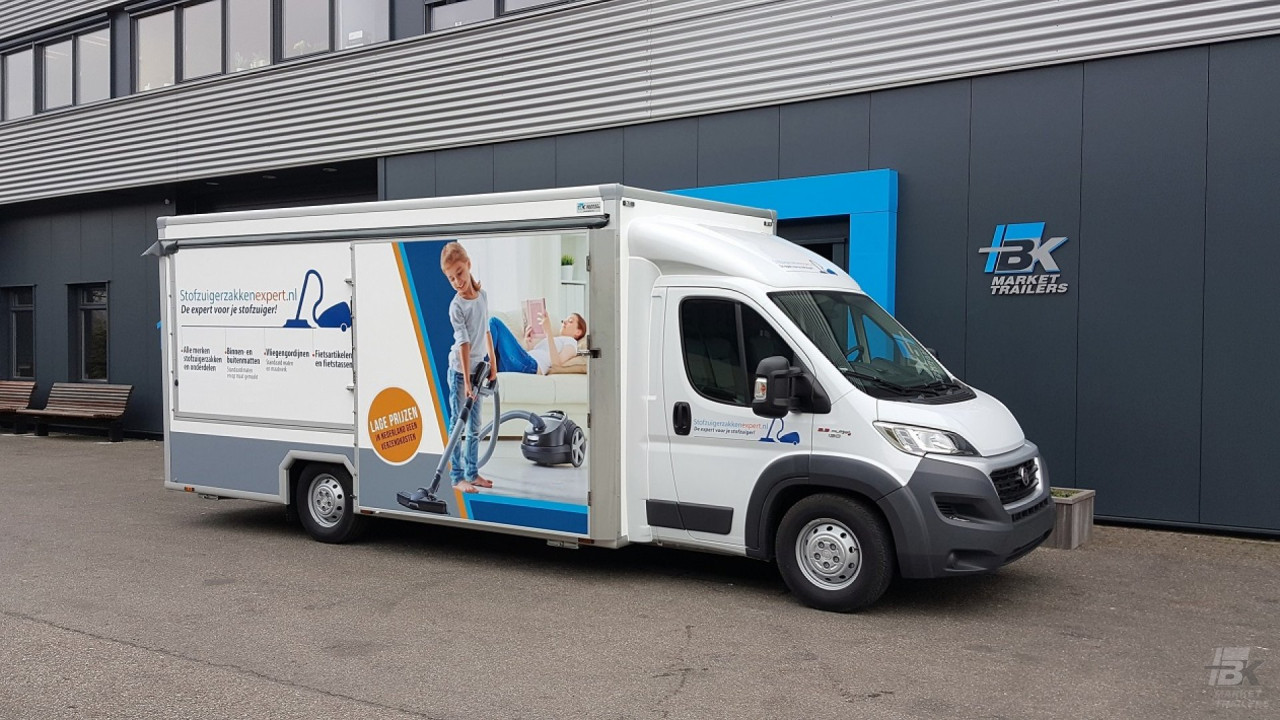 Zijaanzicht van een verkoopwagen voor stofzuigerzakken met gesloten luifel