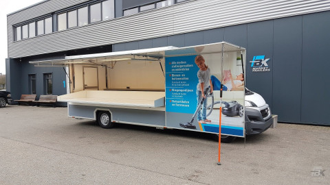 Zijaanzicht van een verkoopwagen voor stofzuigerzakken met geopende luifel