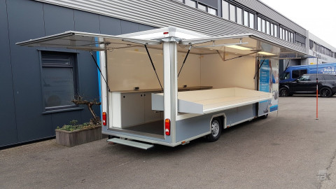 Zijaanzicht van een verkoopwagen voor stofzuigerzakken met geopende luifel