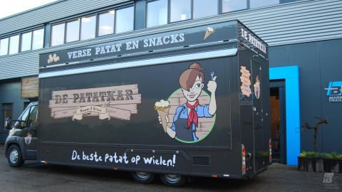Zijaanzicht van een verkoopwagen voor patat met gesloten luifel