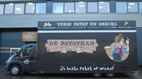 Zijaanzicht van een verkoopwagen voor patat met gesloten luifel
