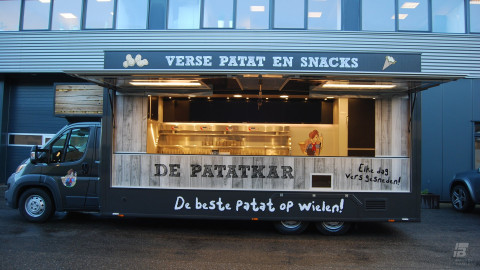 Zijaanzicht van een verkoopwagen voor patat met geopende luifel