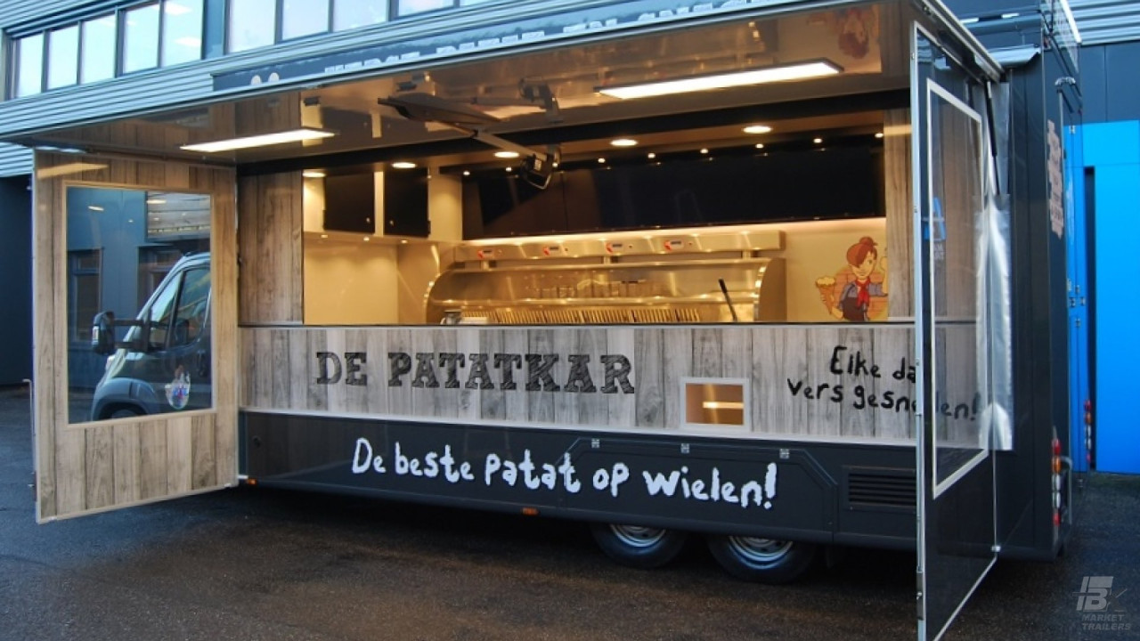 Zijaanzicht van een verkoopwagen voor patat met geopende luifel en zijborden