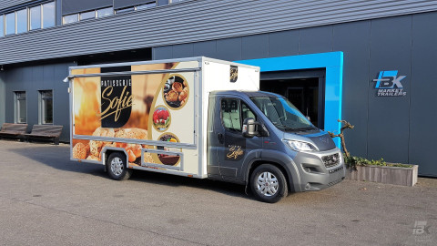 Zijaanzicht van een verkoopwagen voor gebak met gesloten luifel