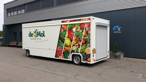 Zijaanzicht van een aanhangwagen voor groente en fruit met gesloten luifel