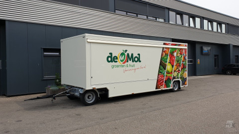Zijaanzicht van een aanhangwagen voor groente en fruit met gesloten luifel