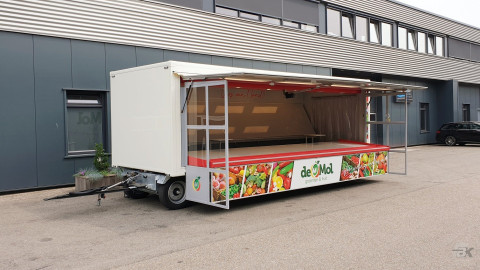 Zijaanzicht van een aanhangwagen voor groente en fruit met geopende luifel