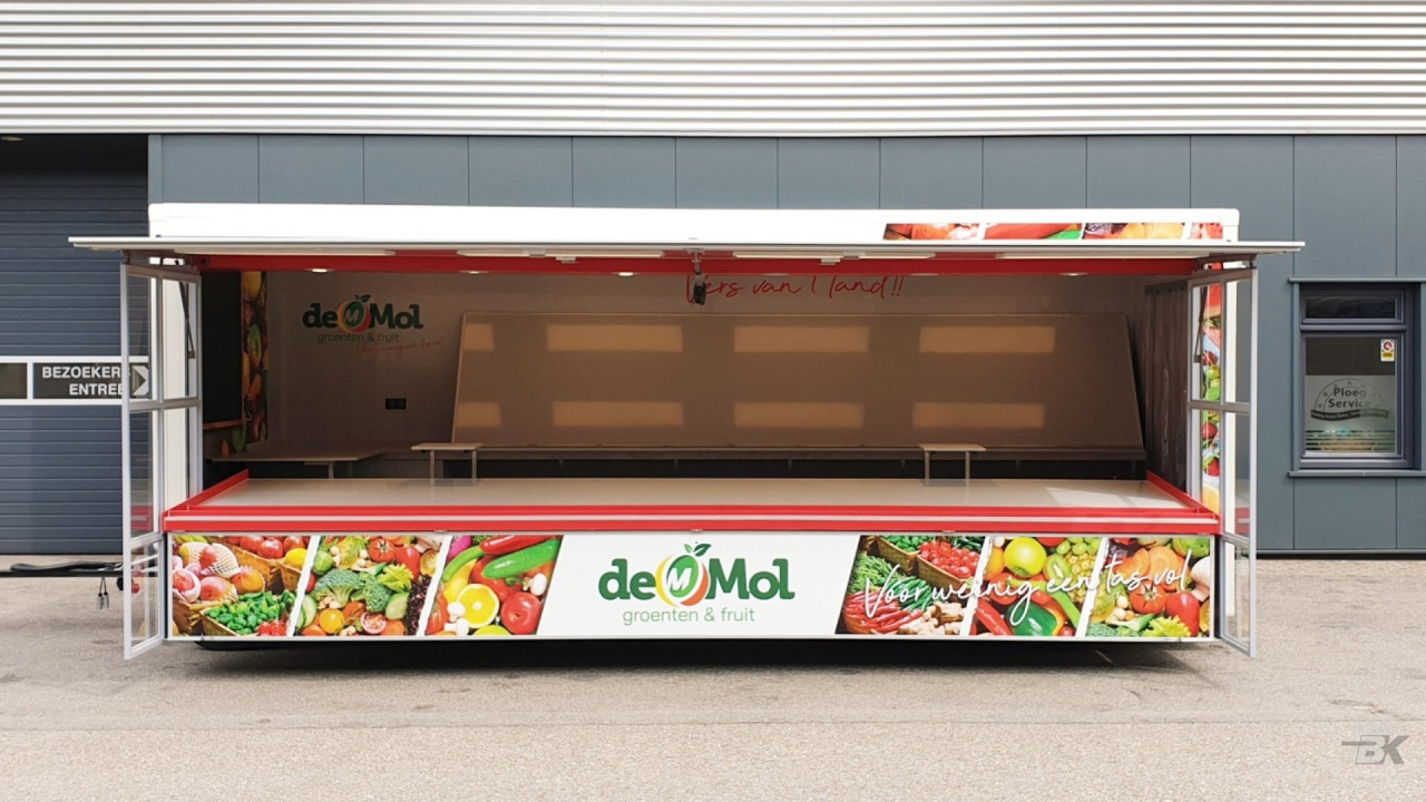Zijaanzicht van een aanhangwagen voor groente en fruit met geopende luifel