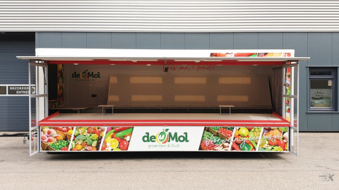 Zijaanzicht van een aanhangwagen voor groente en fruit met geopende luifel