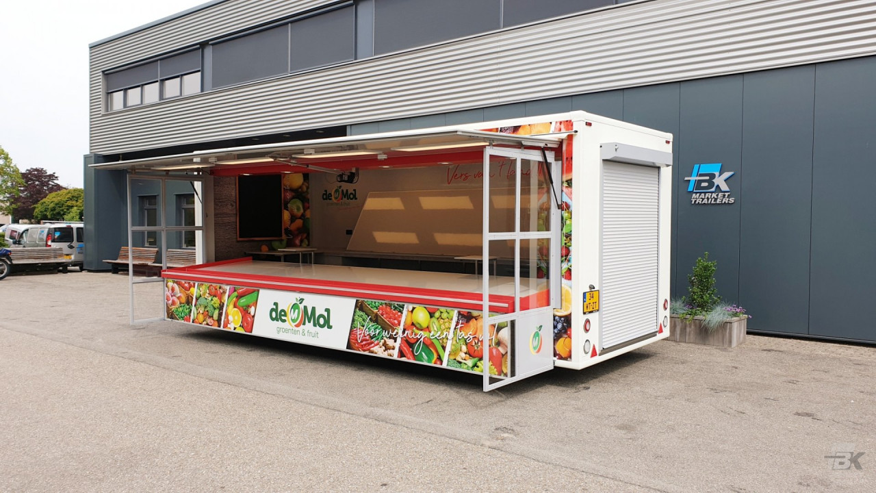 Zijaanzicht van een aanhangwagen voor groente en fruit met geopende luifel