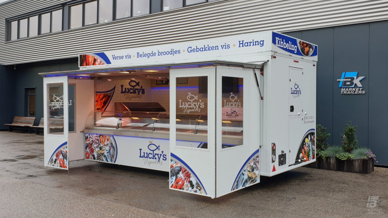 Zijaanzicht van een verkoopwagen voor vis met geopende luifel en zijborden