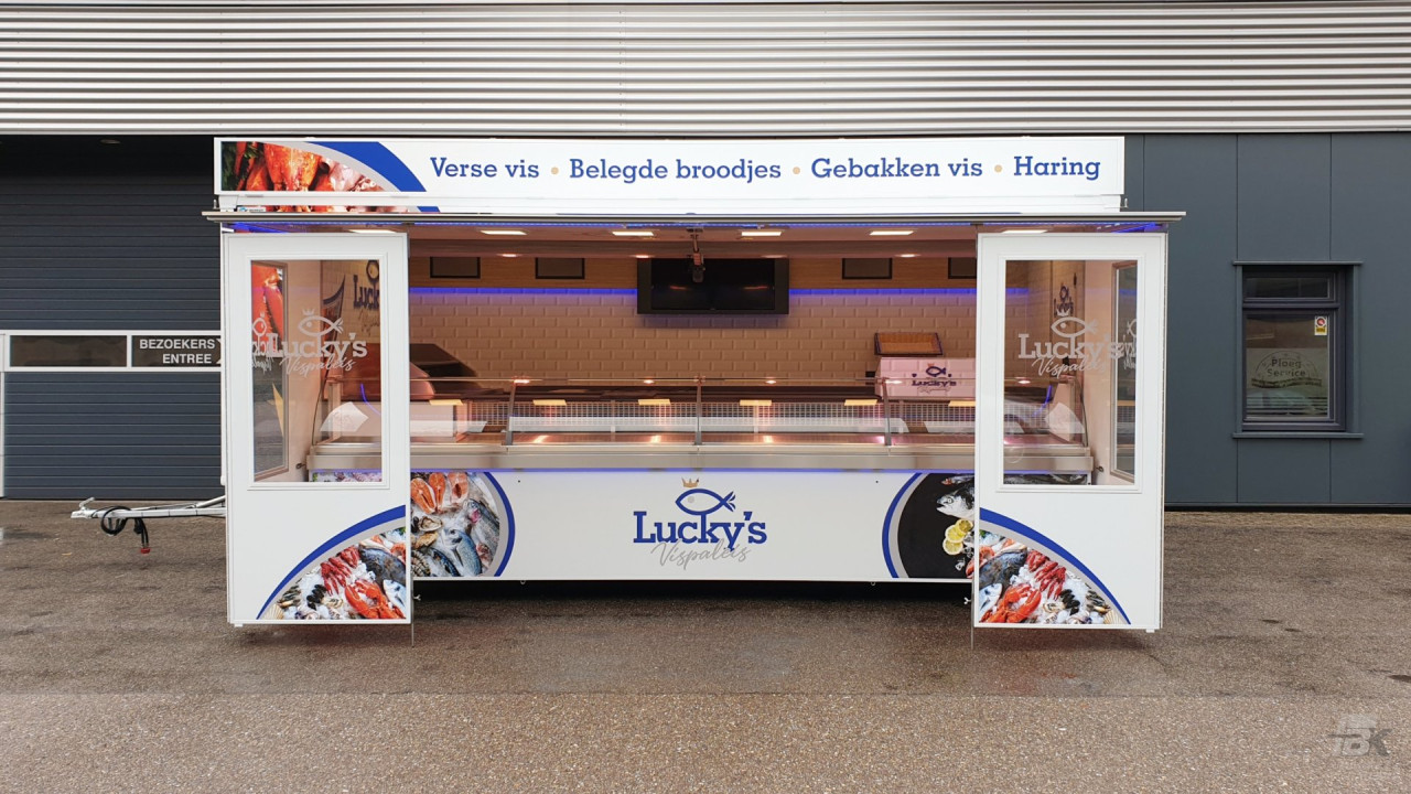 Zijaanzicht van een verkoopwagen voor vis met geopende luifel en zijborden