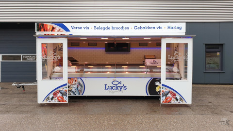 Zijaanzicht van een verkoopwagen voor vis met geopende luifel en zijborden